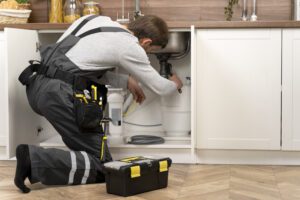 Plumber repairing kitchen sink in a home, providing residential services.